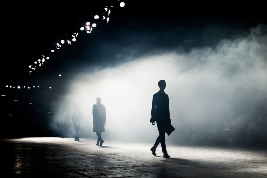 backlit shadow of men's fashion show on dark runway